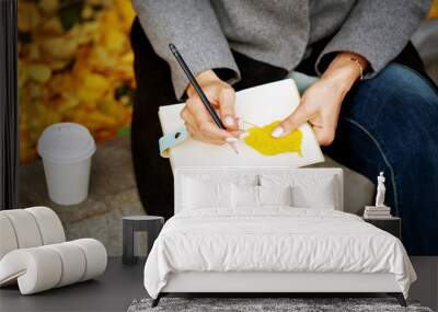 Woman`s hands close-up holding paper notebook and pencil Wall mural